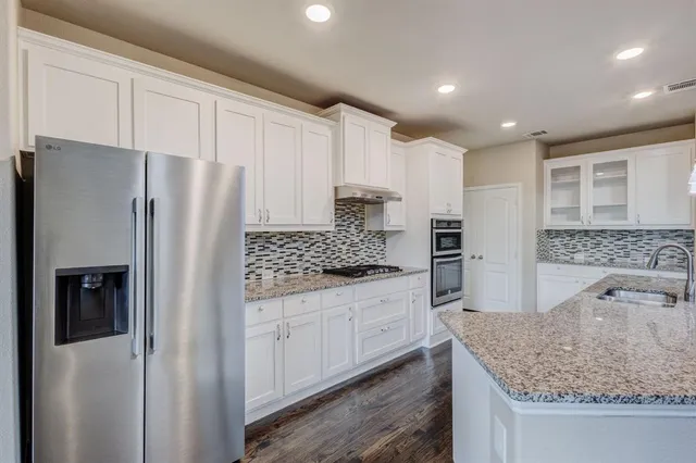 a kitchen with stainless steel appliances granite countertop a refrigerator and a sink