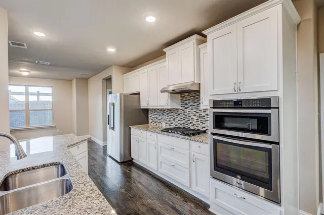 a kitchen with stainless steel appliances granite countertop a stove a sink and a refrigerator