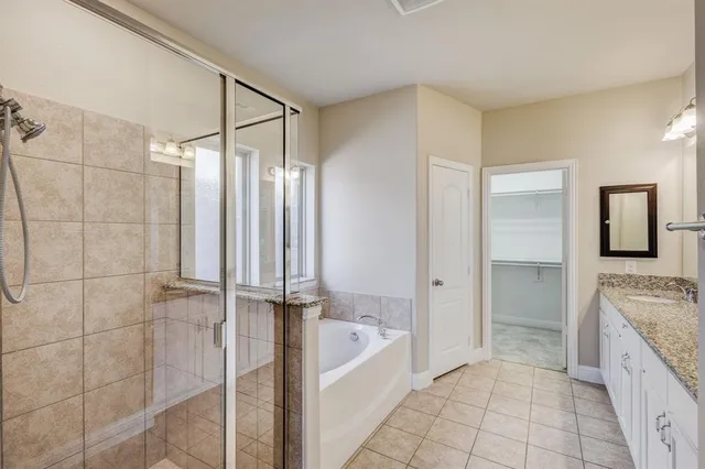 a spacious bathroom with a granite countertop bathtub a sink and a shower