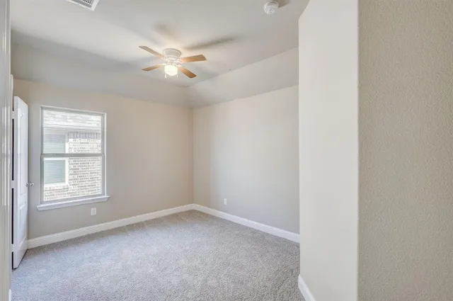 an empty room with a window and a fan