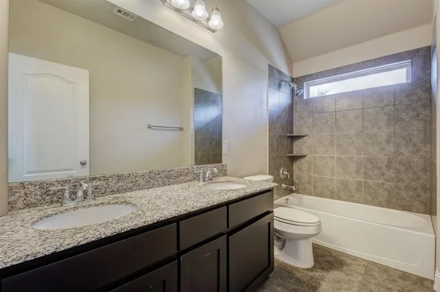 a bathroom with a granite countertop sink toilet mirror and bathtub
