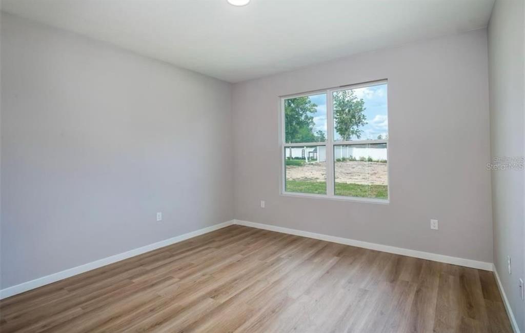 5550 Southwest 107th Street Ocala, FL 34476 - Photo 11 of 17 an empty room with wooden floor and windows