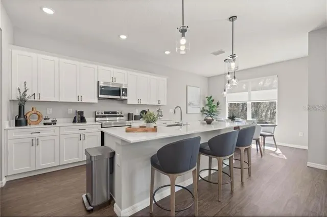 a kitchen with stainless steel appliances a dining table chairs sink and cabinets