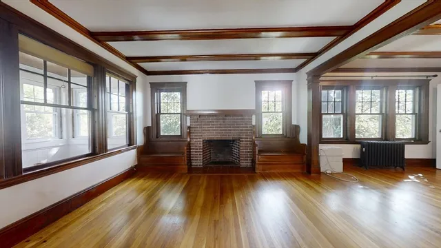 an empty room with wooden floor fireplace and windows