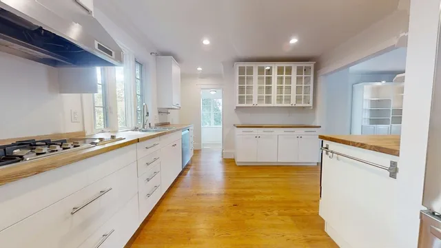 a large white kitchen with kitchen island a stove a sink and a refrigerator with wooden floor