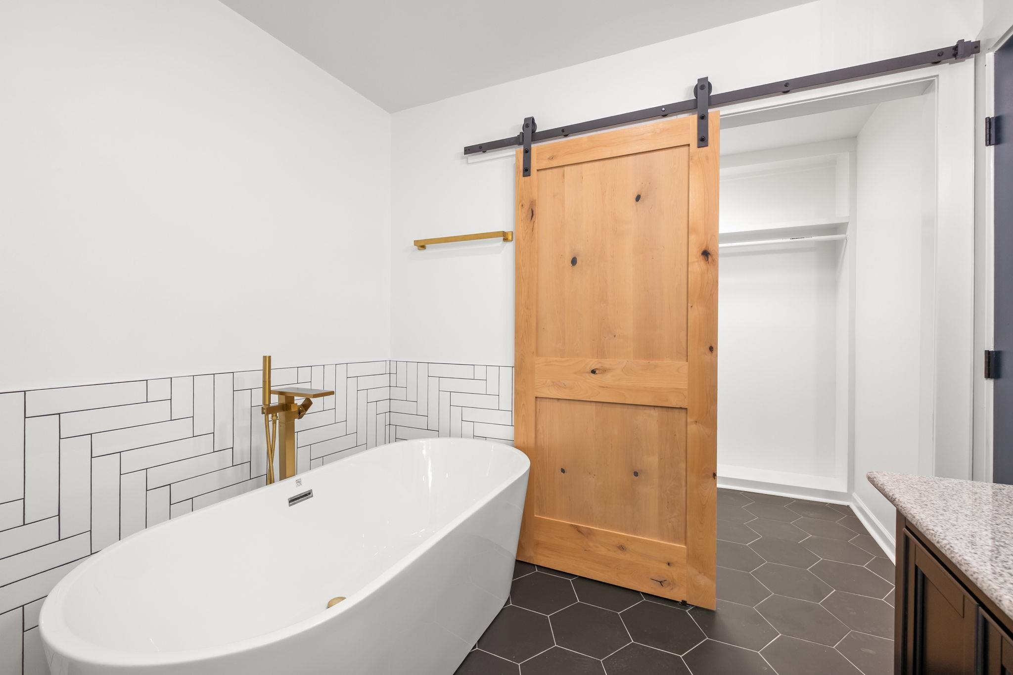 6224 Benjestown Road Memphis, TN 38127 - Photo 24 of 39 Full bath featuring a freestanding bath, tile walls, vanity, dark tile patterned floors, and a wainscoted wall