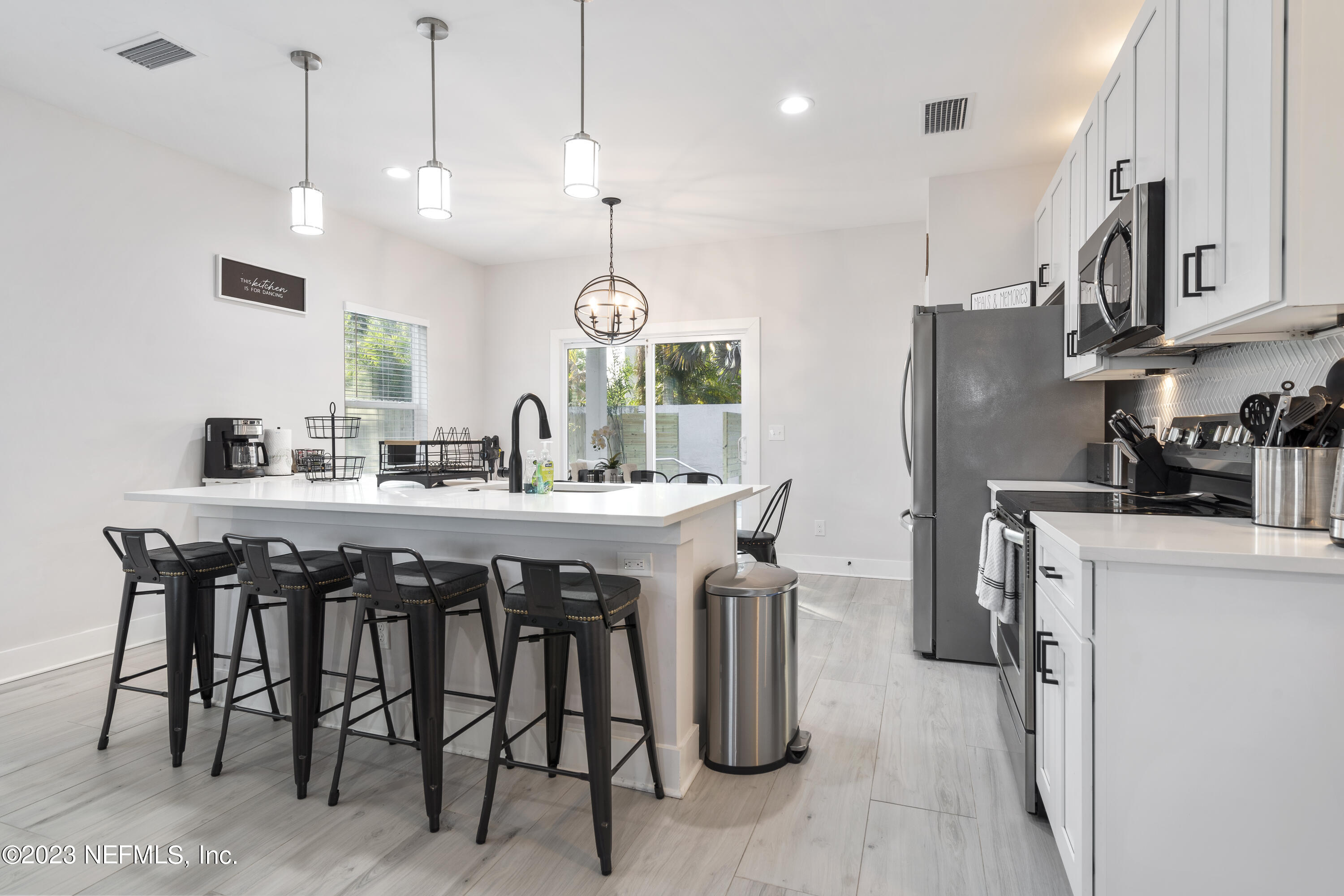 310 3rd Street St. Augustine, FL 32084 - Photo 11 of 46 a kitchen with stainless steel appliances granite countertop a table chairs sink refrigerator and microwave