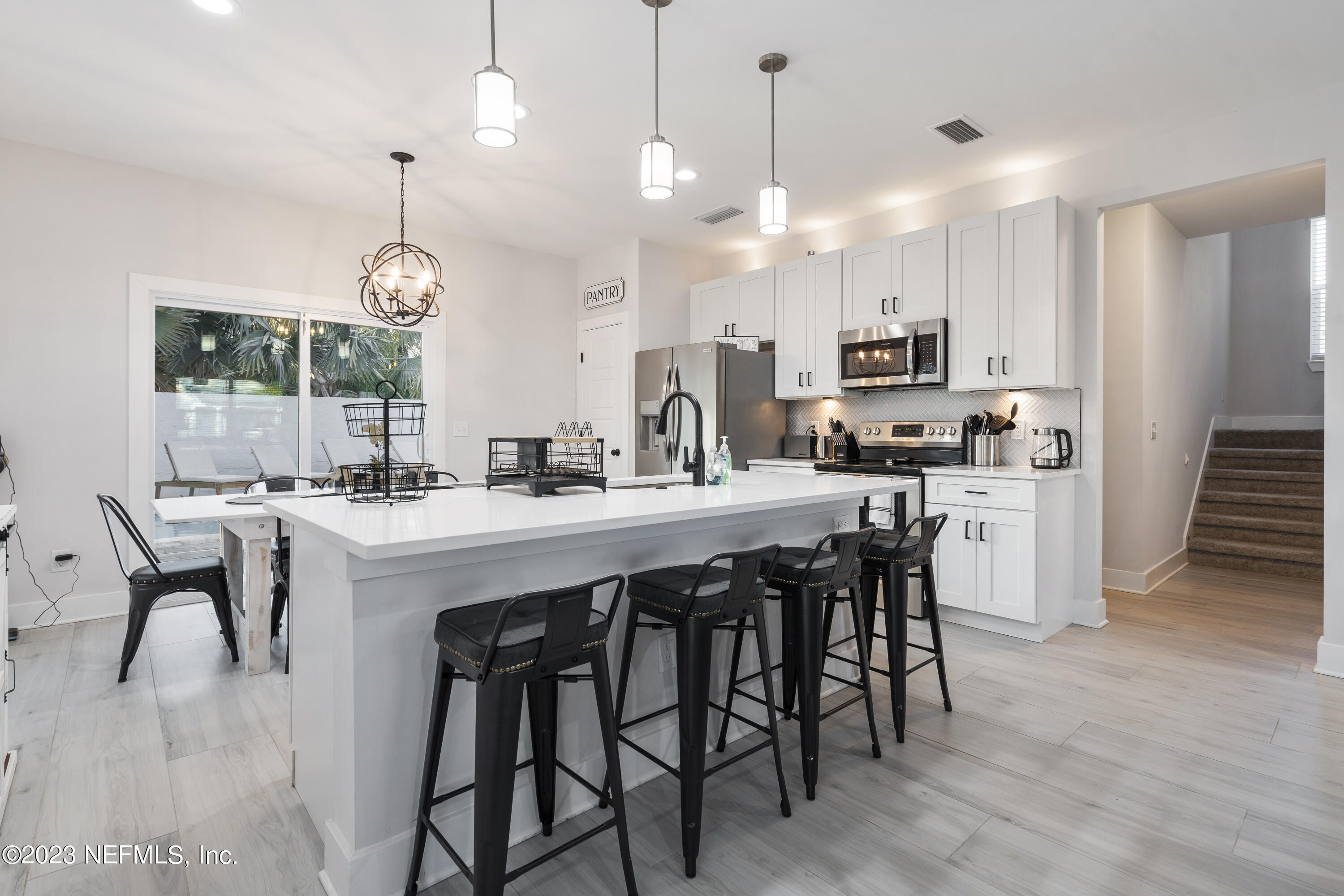 310 3rd Street St. Augustine, FL 32084 - Photo 4 of 46 a kitchen with kitchen island a dining table chairs and a wooden floor
