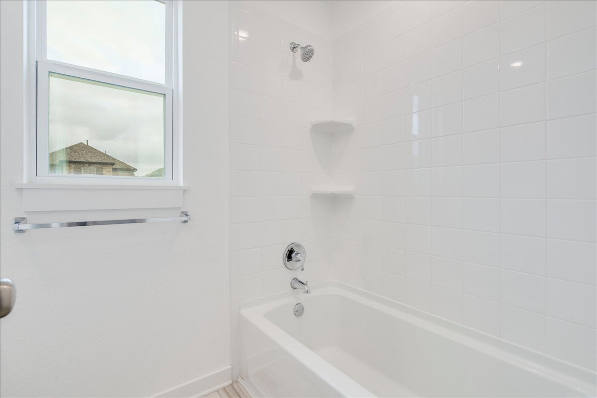 8008 Prairie Rye Drive Lago Vista, TX 78645 - Photo 26 of 40 Second full bathroom upstairs with white tiled shower and tub combination featuring chrome fixtures