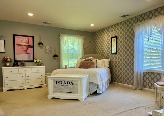 a bedroom with a bed a mirror on dresser and a window