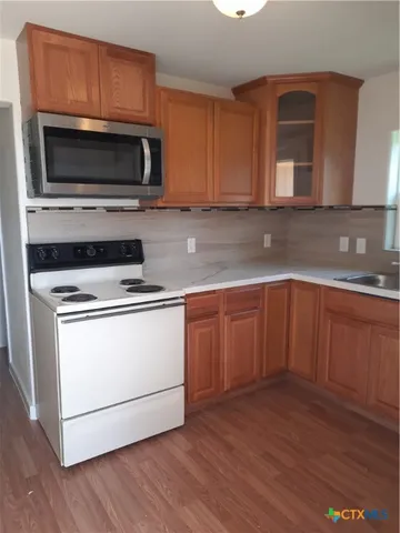 a kitchen with granite countertop wooden cabinets stainless steel appliances and a sink