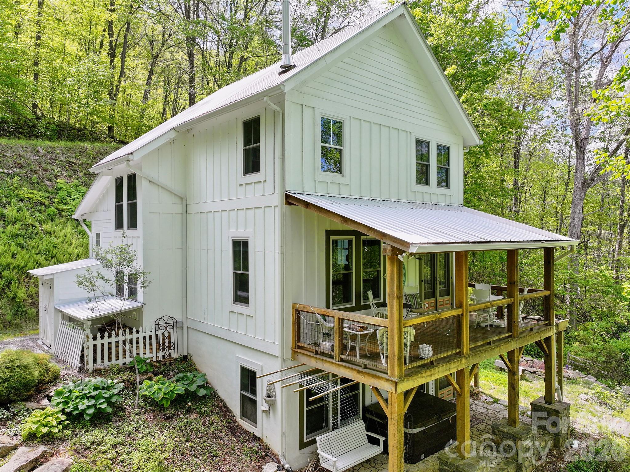 580 Split Pine Cove Clyde, NC 28721 - Photo 2 of 30 a view of a white house with large windows and wooden fence