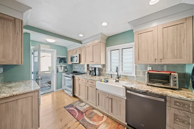 a kitchen with stainless steel appliances granite countertop a sink stove refrigerator and cabinets