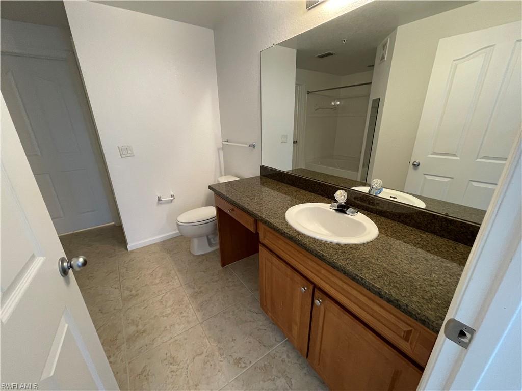 12940 Positano Circle, Unit 202 Naples, FL 34105 - Photo 15 of 33 a bathroom with a granite countertop sink and a mirror