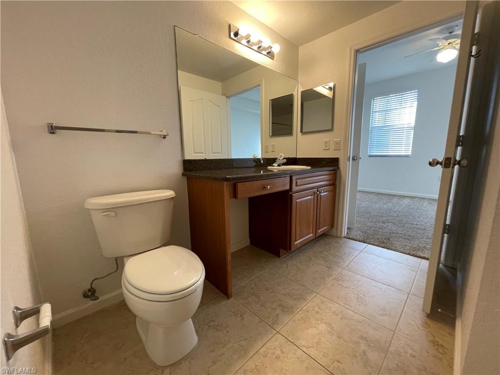 12940 Positano Circle, Unit 202 Naples, FL 34105 - Photo 16 of 33 a bathroom with a granite countertop toilet sink and mirror