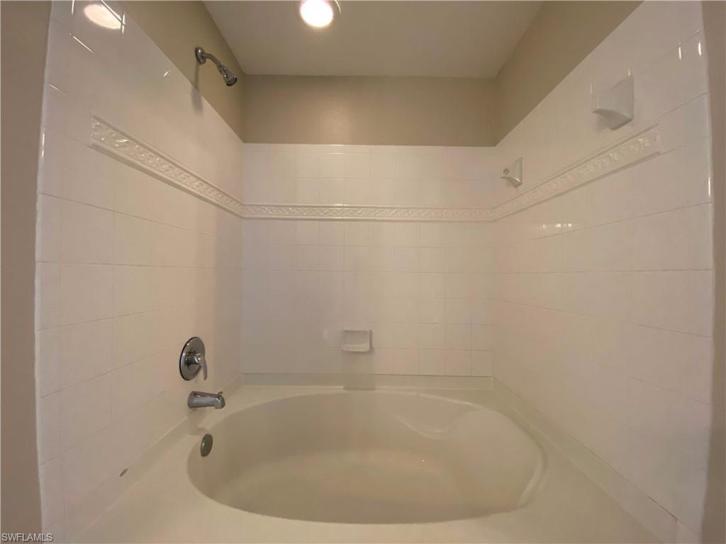 12940 Positano Circle, Unit 202 Naples, FL 34105 - Photo 17 of 33 a bathroom with a white bath tub and a shower