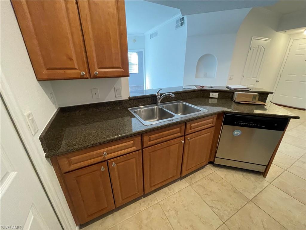 12940 Positano Circle, Unit 202 Naples, FL 34105 - Photo 7 of 33 a kitchen with stainless steel appliances a sink dishwasher stove and cabinets