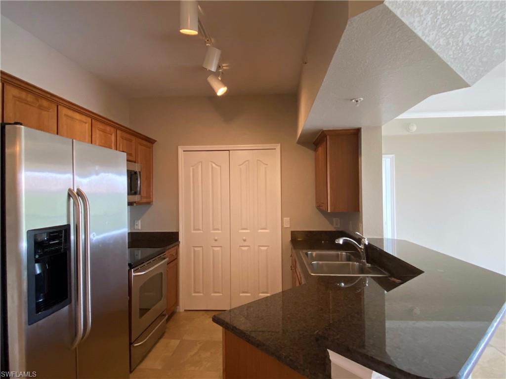 12940 Positano Circle, Unit 202 Naples, FL 34105 - Photo 8 of 33 a kitchen with stainless steel appliances granite countertop a refrigerator and a counter top