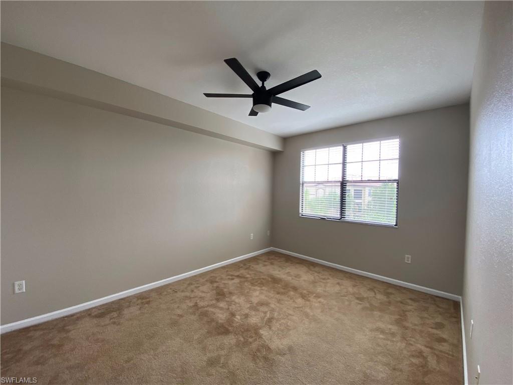 12940 Positano Circle, Unit 202 Naples, FL 34105 - Photo 9 of 33 an empty room with a window and a fan