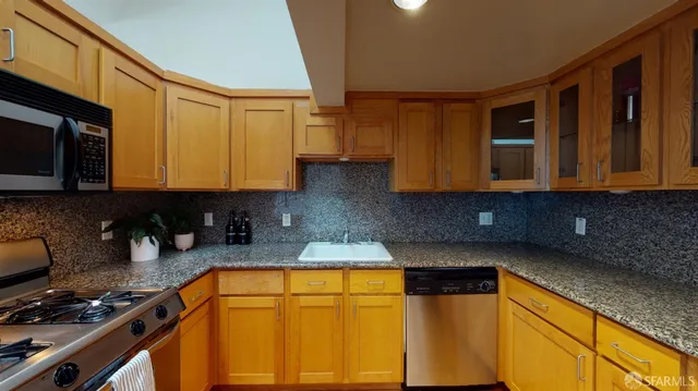 a kitchen with stainless steel appliances granite countertop sink stove top oven and cabinets