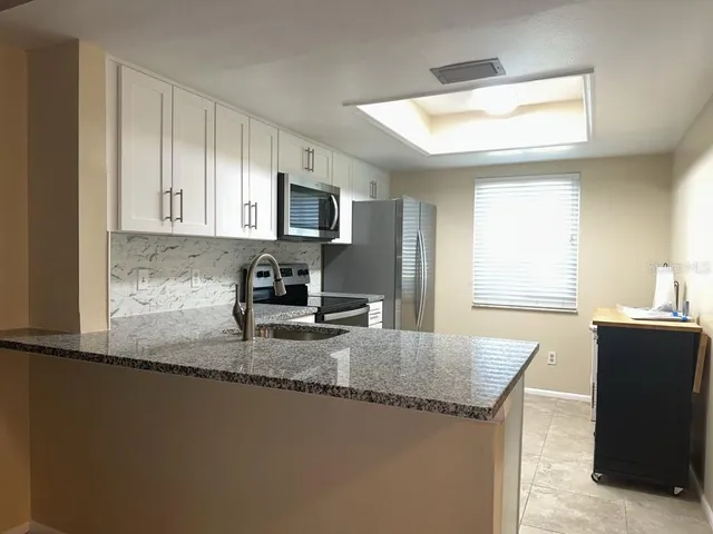 a kitchen with granite countertop a sink a counter top space and cabinets