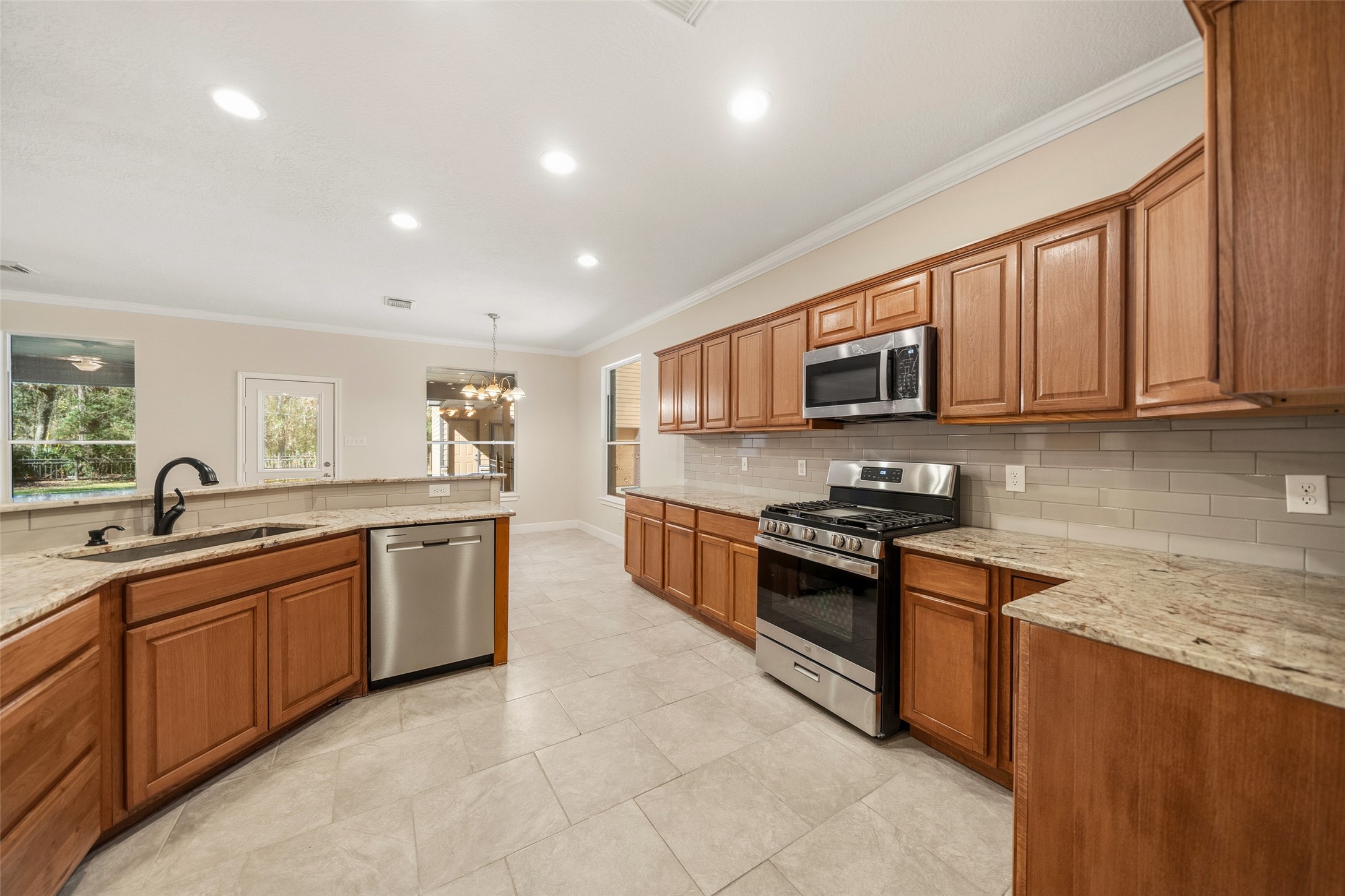29627 Spring Forest Drive Spring, TX 77386 - Photo 10 of 35 a large kitchen with stainless steel appliances granite countertop a stove top oven a sink dishwasher and a microwave oven with cabinets
