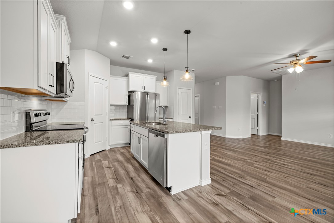 6243 Matagorda Road Belton, TX 76513 - Photo 15 of 27 a kitchen with stainless steel appliances kitchen island granite countertop a stove a sink a refrigerator and white cabinets with wooden floor