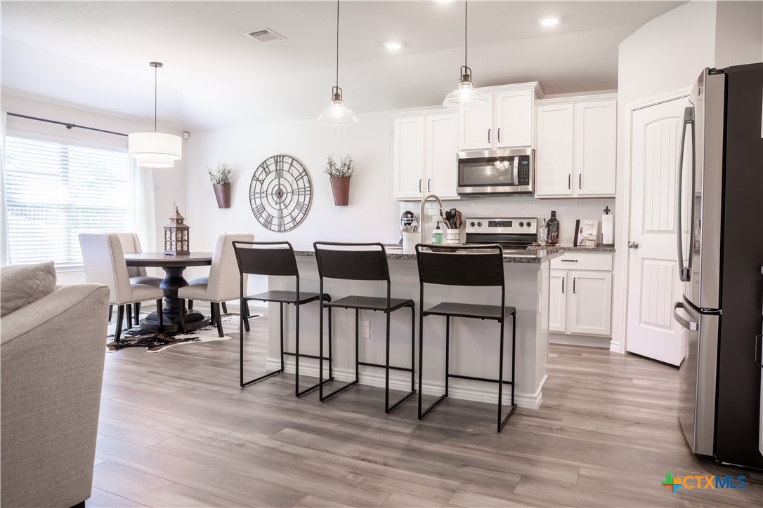 6243 Matagorda Road Belton, TX 76513 - Photo 5 of 27 a kitchen with stainless steel appliances a dining table chairs stove microwave and cabinets