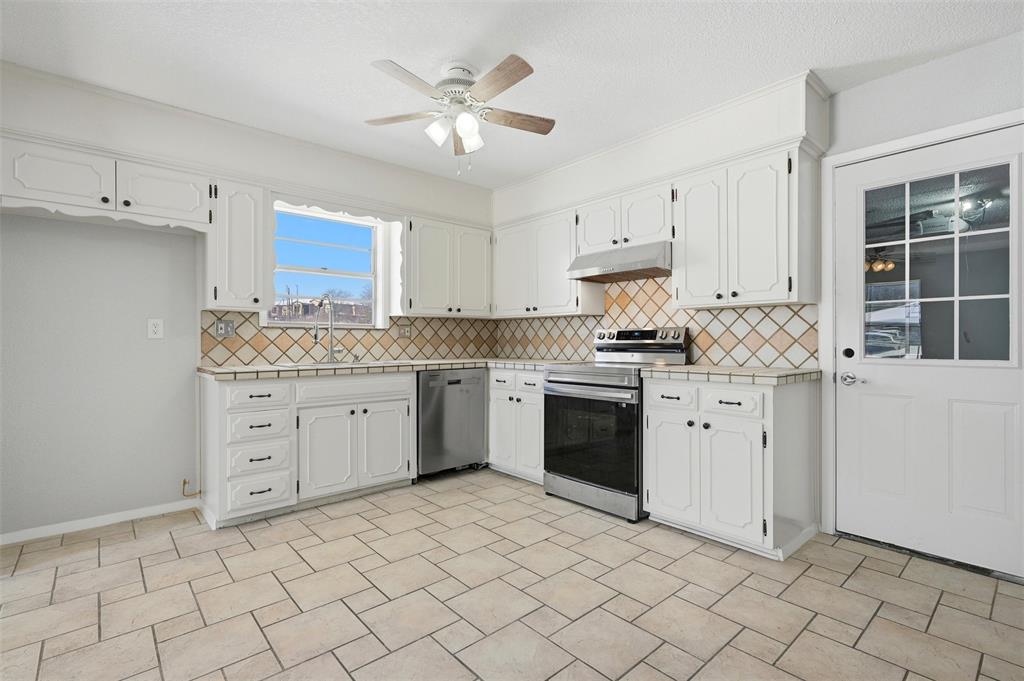 2611 Easy Street Denison, TX 75020 - Photo 12 of 32 a kitchen with granite countertop white cabinets stainless steel appliances a sink and a window