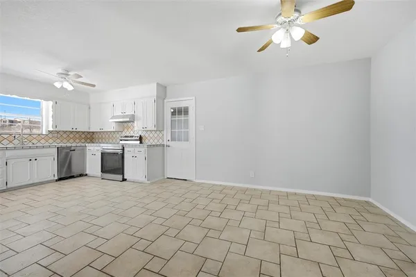 a kitchen with white cabinets a sink stainless steel appliances and a chandelier