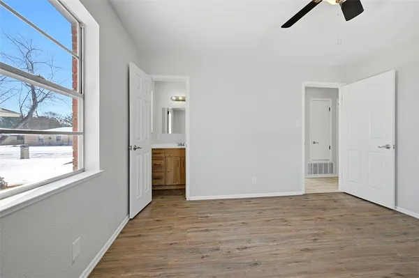 a view of an empty room with a window and wooden floor