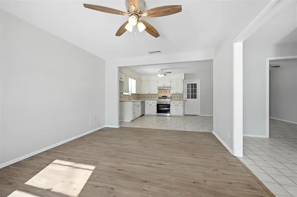 a view of empty room with wooden floor and kitchen view