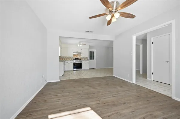 a view of empty room with wooden floor and ceiling fan