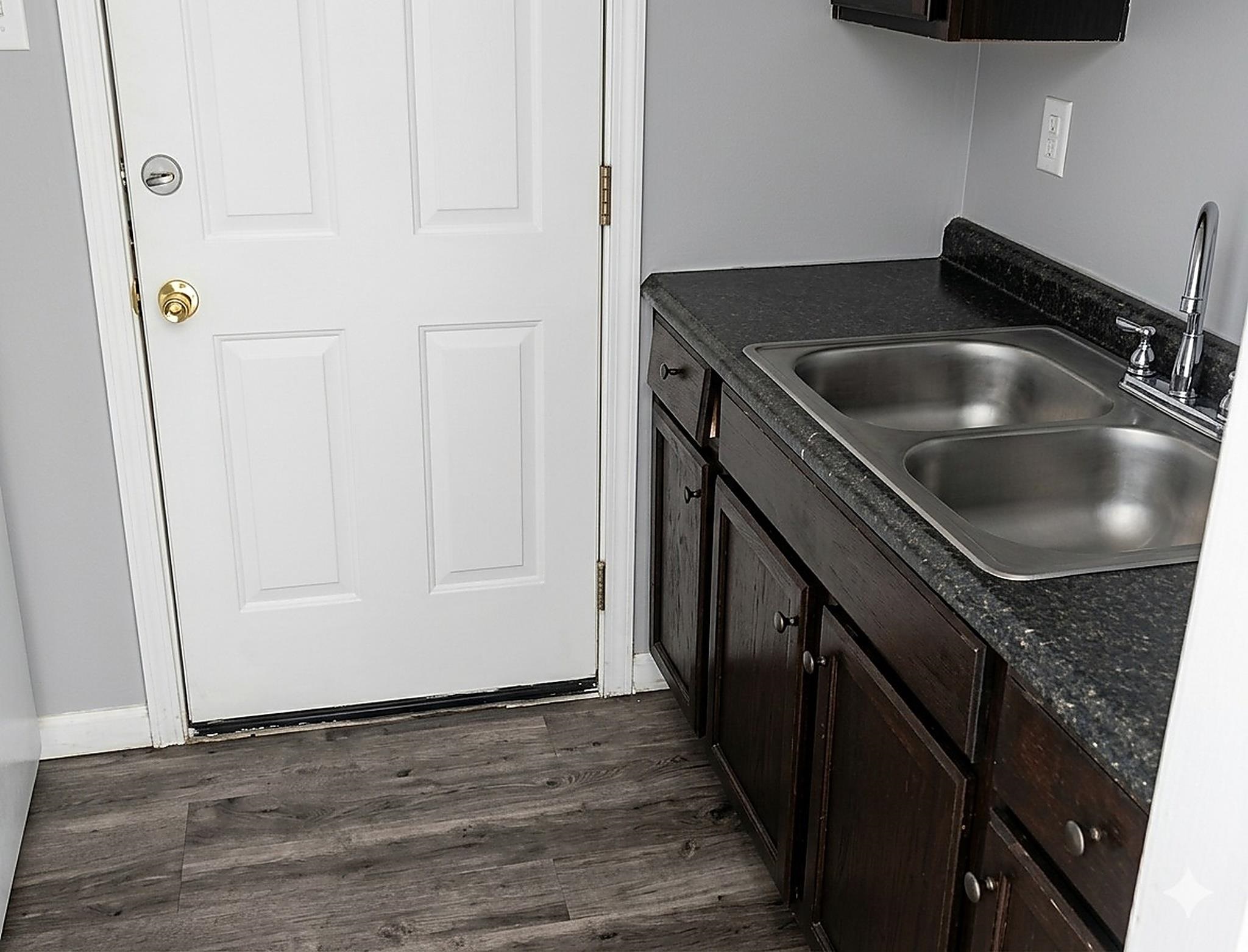 4444-4446 Sumners Wells Road Memphis, TN 38118 - Photo 5 of 8 Kitchenette area featuring a double basin stainless steel sink with a chrome faucet, dark wood-finish cabinetry, and a speckled countertop