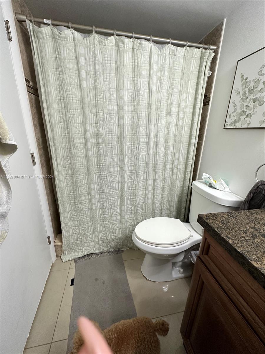 15821 Southwest 104th Terrace, Unit 203 Miami, FL 33196 - Photo 14 of 25 a white toilet sitting next to a shower curtain