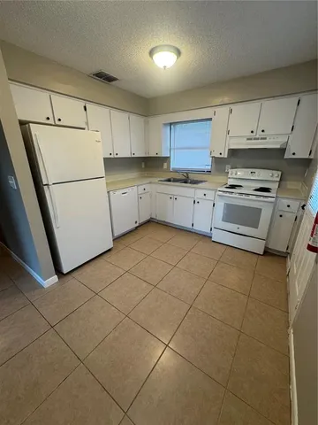 a kitchen with a stove a refrigerator and white cabinets
