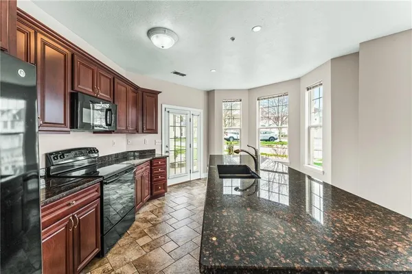 a kitchen with granite countertop a stove a sink and a dining table