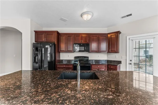 a kitchen with kitchen island granite countertop a refrigerator and a stove top oven