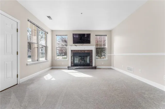 a view of an empty room with a window and a fireplace