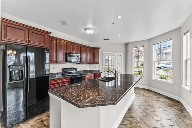 a kitchen with kitchen island granite countertop a sink stove and refrigerator