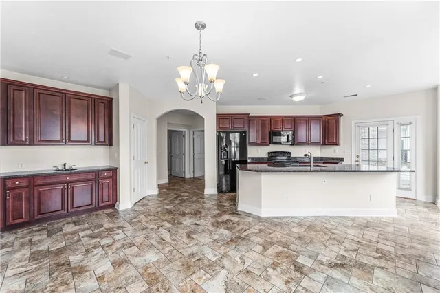 a large kitchen with kitchen island stainless steel appliances granite countertop a stove oven and a sink with granite countertops