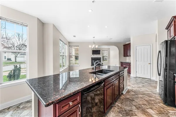 a kitchen with granite countertop kitchen island stainless steel appliances a sink stove and refrigerator