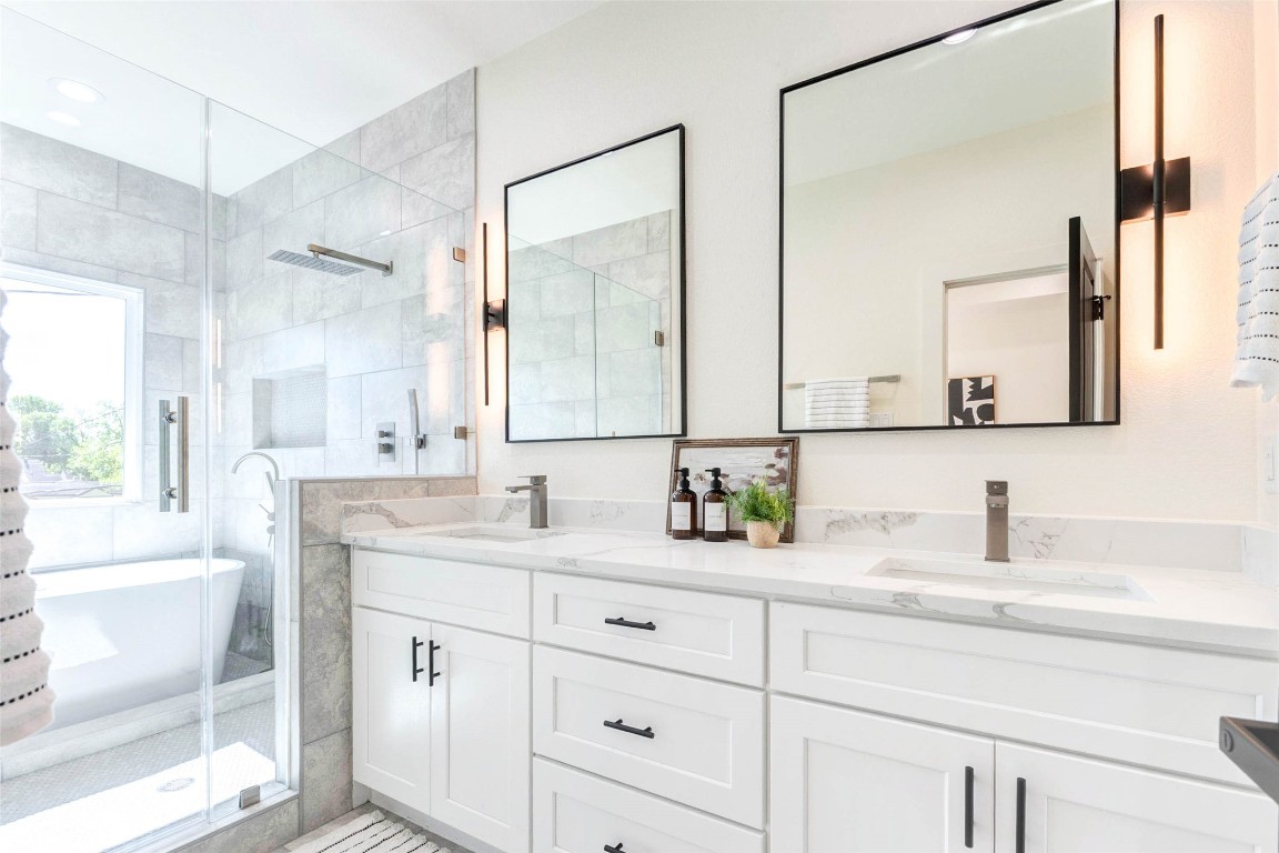 7115 England Street, Unit B Houston, TX 77021 - Photo 9 of 19 The dual-sink vanity is topped with marble-style quartz and accented by minimalist black hardware and vertical sconce lighting.