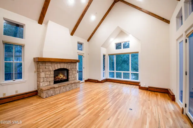 a view of an empty room with wooden floor fireplace and a window