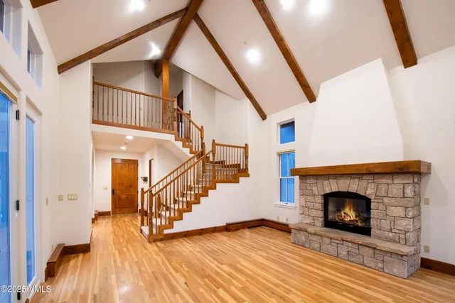a view of an empty room with wooden floor and a fireplace