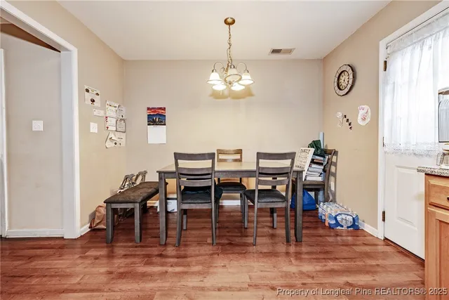 a dining room with wooden floor a chandelier a wooden table and chairs