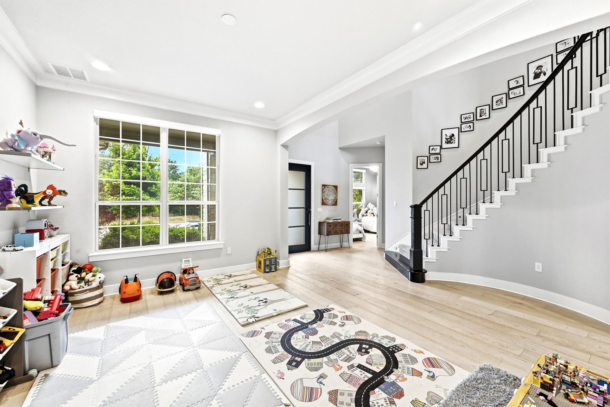 9008 Harper Rae Drive Austin, TX 78717 - Photo 15 of 39 Spacious interior featuring light wood-finish flooring, a contemporary staircase with black wrought iron balusters, a large multi-pane window, recessed lighting, and crown molding