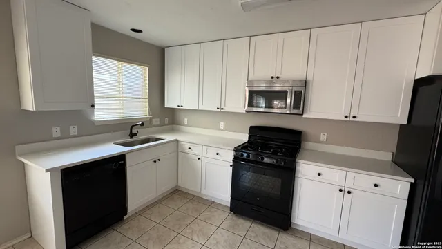 a kitchen with granite countertop white cabinets and black appliances