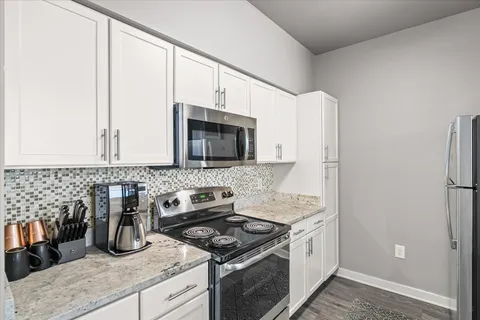 a kitchen with granite countertop a sink stove and refrigerator