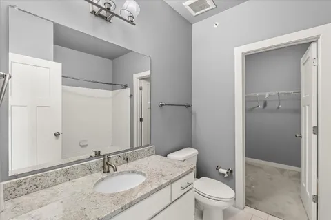 a bathroom with a granite countertop sink toilet a mirror and shower